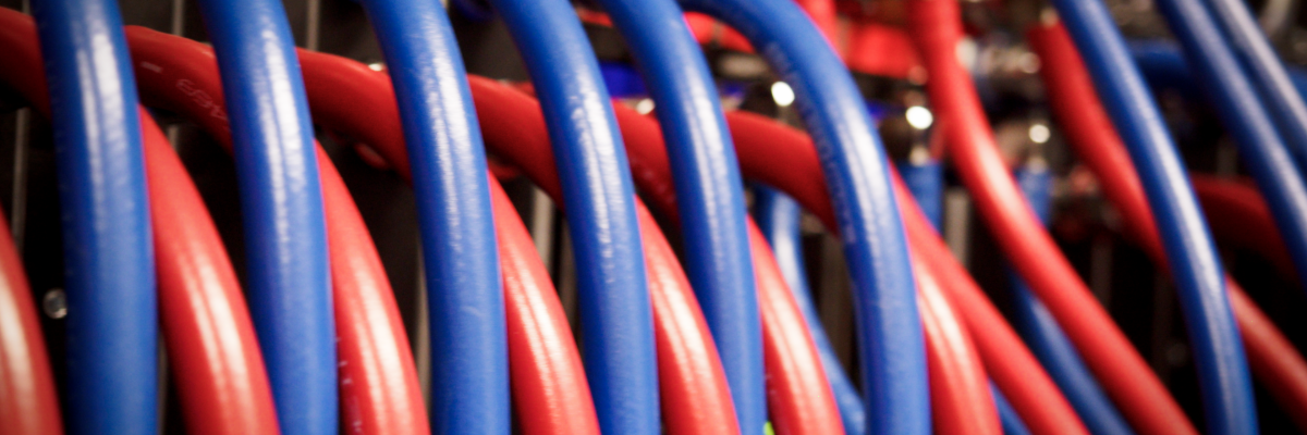 Close-up of red and blue high-performance network cables inside the Isambard-AI supercomputer infrastructure, showing the physical connectivity that supports large-scale AI and research workloads.