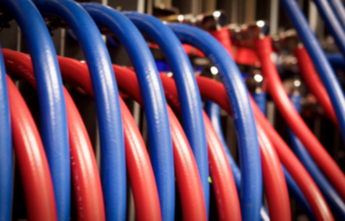 Close-up of red and blue high-performance network cables inside the Isambard-AI supercomputer infrastructure, showing the physical connectivity that supports large-scale AI and research workloads.